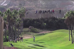 Migrants on a fence above a golf course