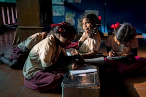 School girls sitting on the floor of a classroom