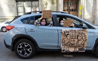 People hold signs from a car window