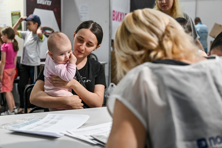 A woman holding a baby visits an aid center in Zaporizhzhia, Ukraine, on June 30, 2022.
© Dmytro Smolyenko/Ukrinform/Getty A woman holding a baby at a desk