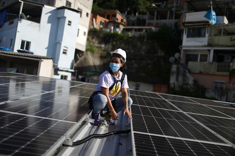 Mulher com capacete de segurança em telhado coberto de painéis solares