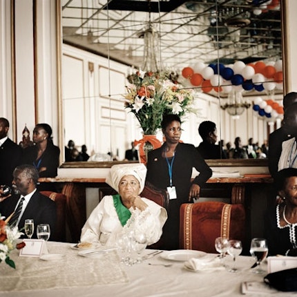 Ellen Johnson-Sirleaf, president of Liberia, inauguration celebration, 2006. Photo credit: © Tim Hetherington/Magnum Photos Woman sitting at dining table.