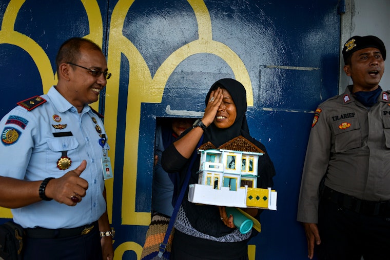 A woman is released from prison in an effort to reduce the spread of COVID-19, near Banda Aceh, Indonesia, on April 6, 2020. Photo credit: © Chaideer Mahyuddin/AFP/Getty A woman celebrates after being released from prison