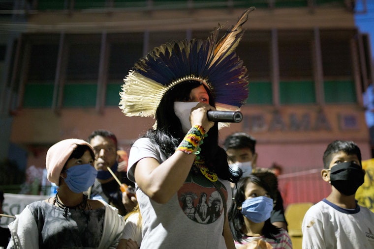 Uma mulher usando uma máscara de proteção facial fala em uma manifestação internacional pelo clima