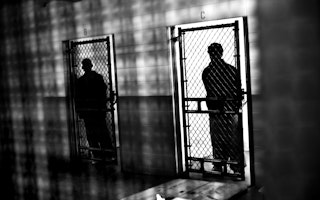 Silhouetted figures in adjacent prison cells