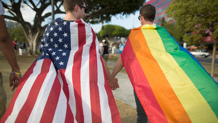Two men in West Hollywood, California, celebrate the United States Supreme Court ruling on same-sex marriage on June 26, 2015. Photo credit: © David McNew/Getty Two men walking wearing flags