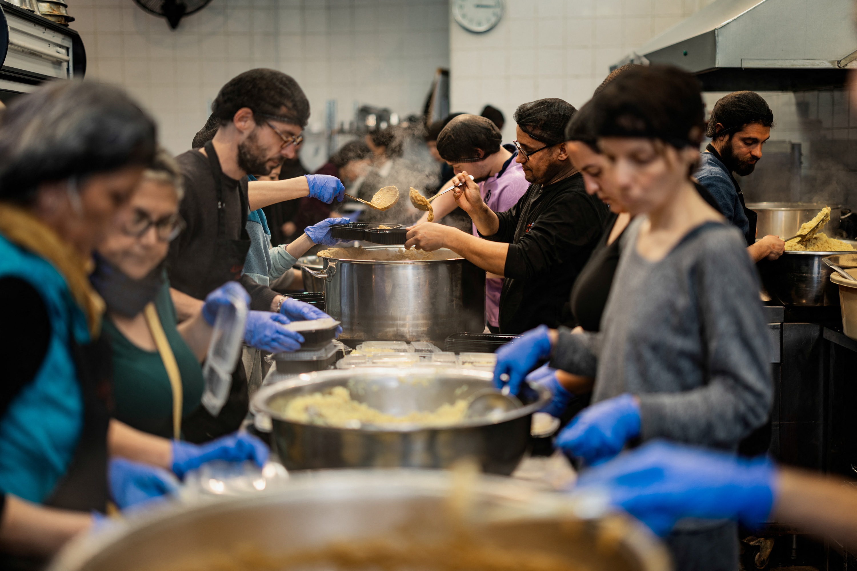 People gathered around large pots in a large kitchen
