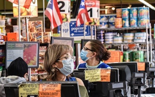 Two women at the registers in a grocery store