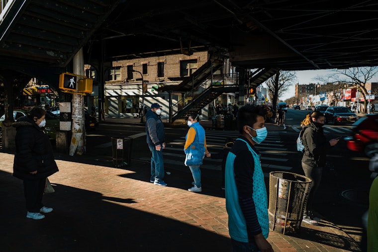 Pedestrians are seen wearing face masks in a predominantly immigrant neighborhood, in the Queens borough of New York City, on March 27, 2020. People wearing face masks walk down a street in a crowded city
