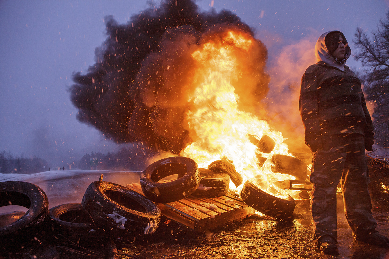 Person stands near burning tires