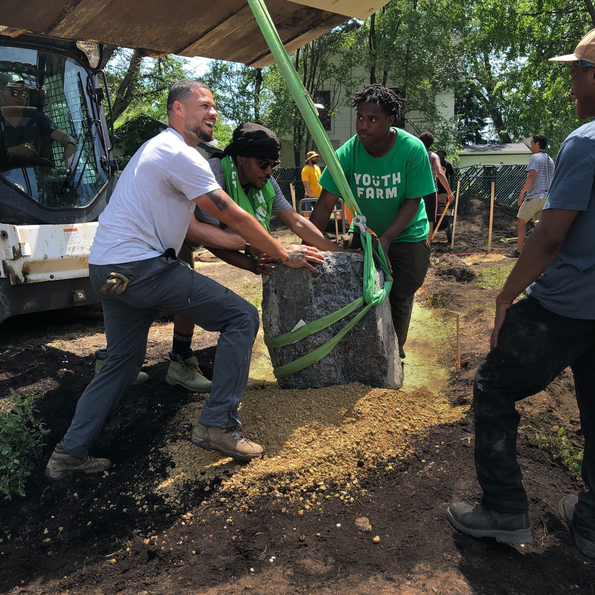 Three people lift a large piece of cement.