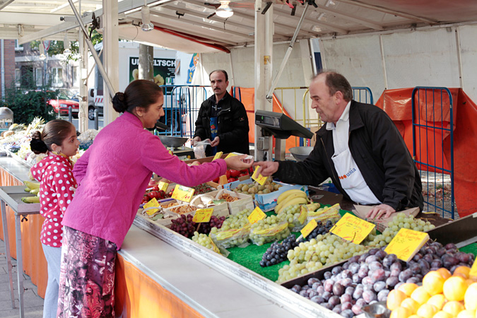 Woman at fruit stand handing money to worker