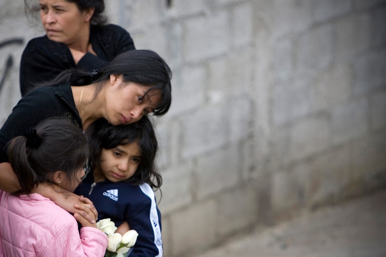 A woman hugging two young girls