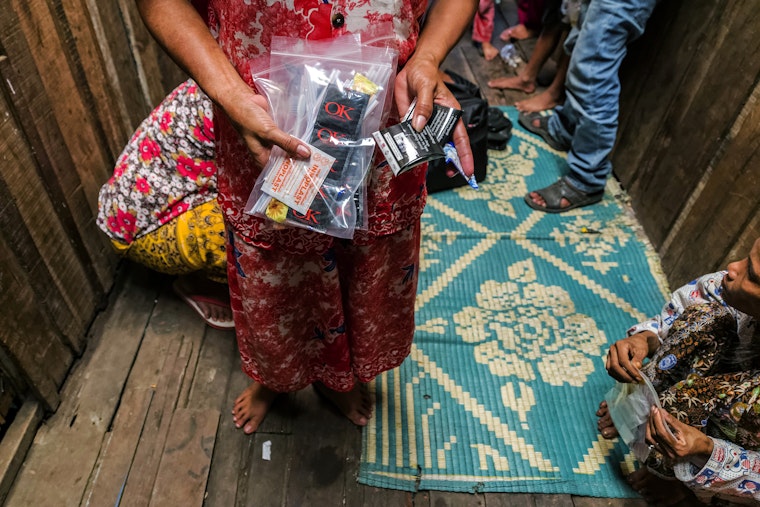 Staff at a health education and services NGO provide free condoms to people in Phnom Penh, Cambodia, on May 7, 2015. Photo credit: © Paola Di Bella/Redux A person holding condom packages