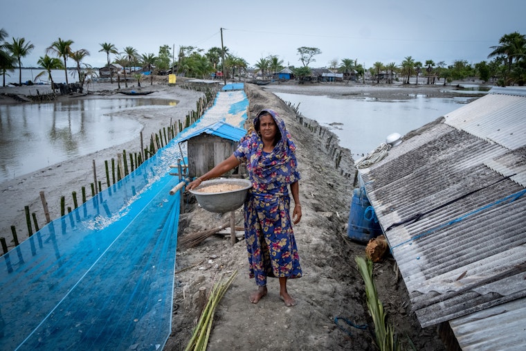 A farmer in a village where rising sea levels have forced many people to migrate in Satkhira Province, Bangladesh. © Majority World/Shutterstock A person stands on a sandbar