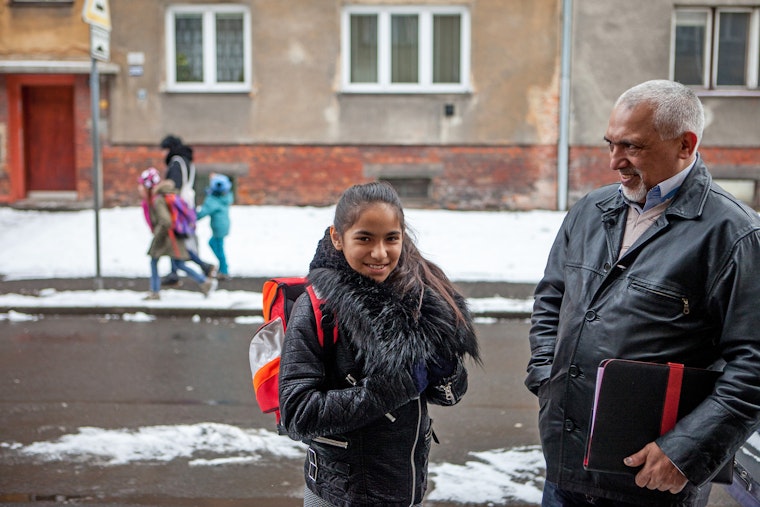 A grade school-aged girl stands with her father outside her school, which educates Roma and non-Roma children together, in Ostrava, Czech Republic. Photo credit: © Bjoern Steinz/Panos for the Open Society Foundations A father and daughter stand next to one another on a snow covered street.