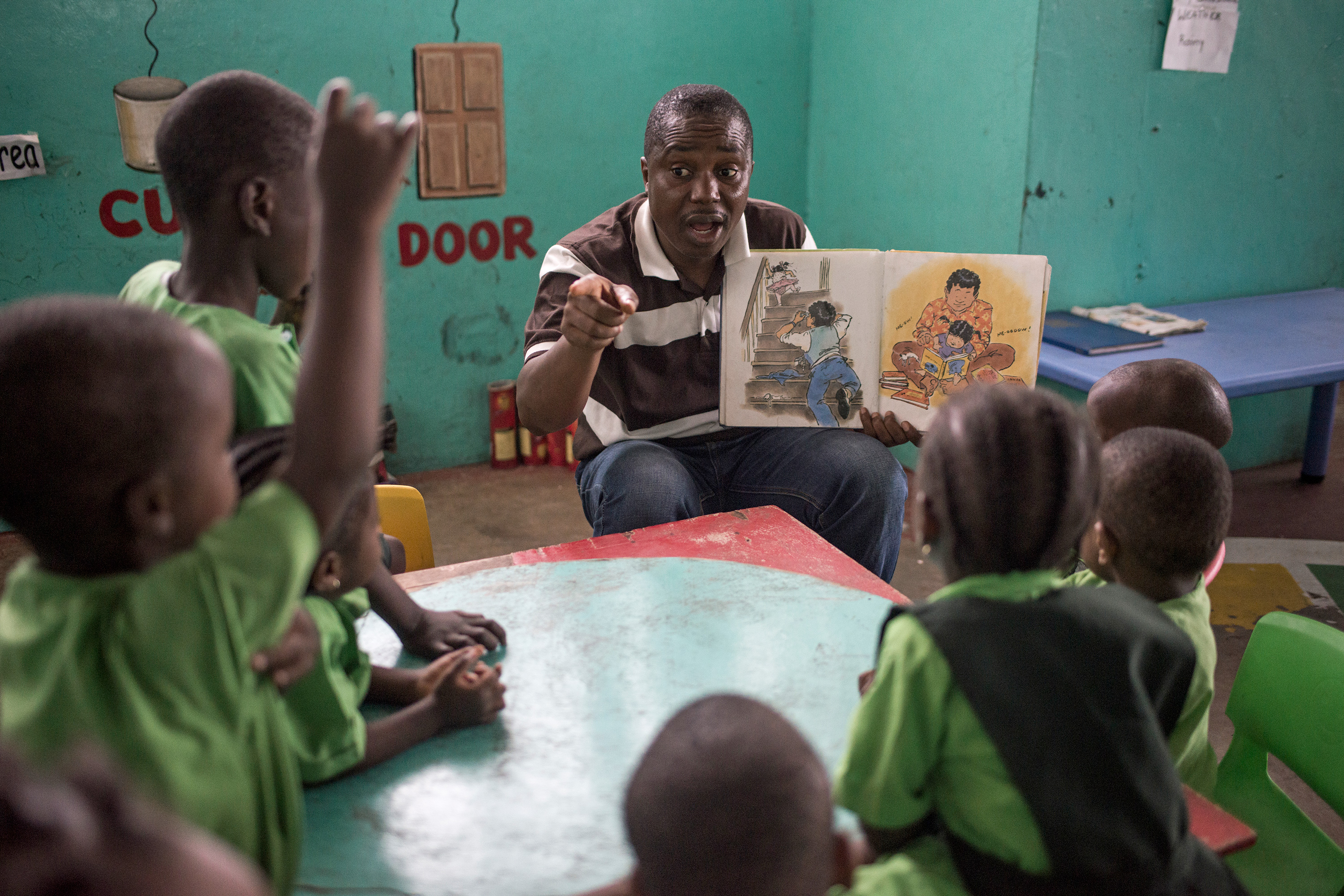 A teacher reading a book to a group of school children